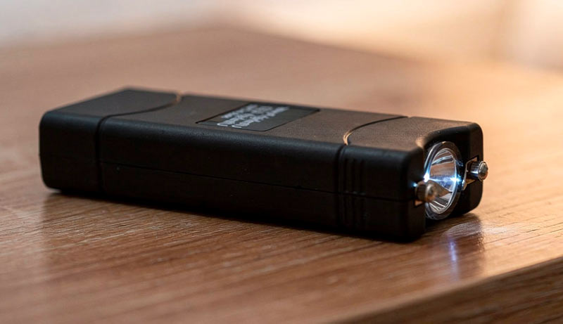 Black rechargeable Safety Kit stun gun resting on a wooden surface